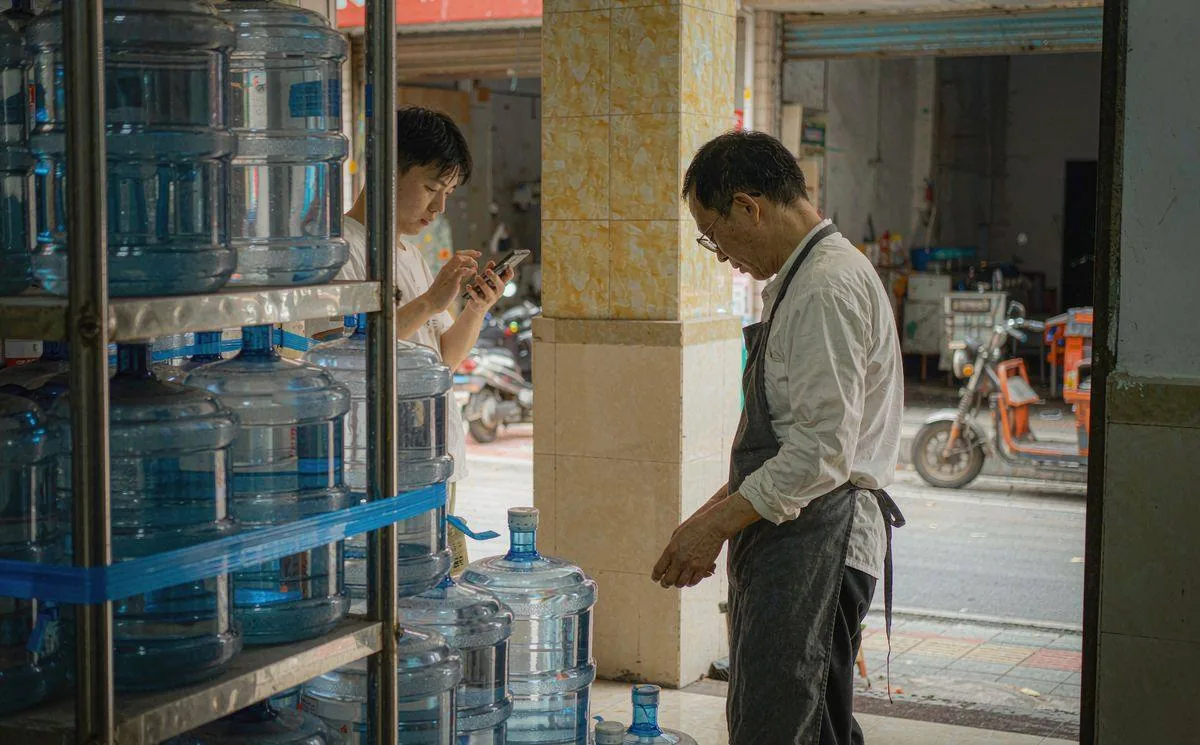 桶装水门店员工码放水桶并通过手机接收订单