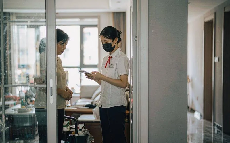 中国配送服务现场,穿工装的服务人员上门与客户当面核对单据并拍照留证,桌面摆放工具包,写实摄影