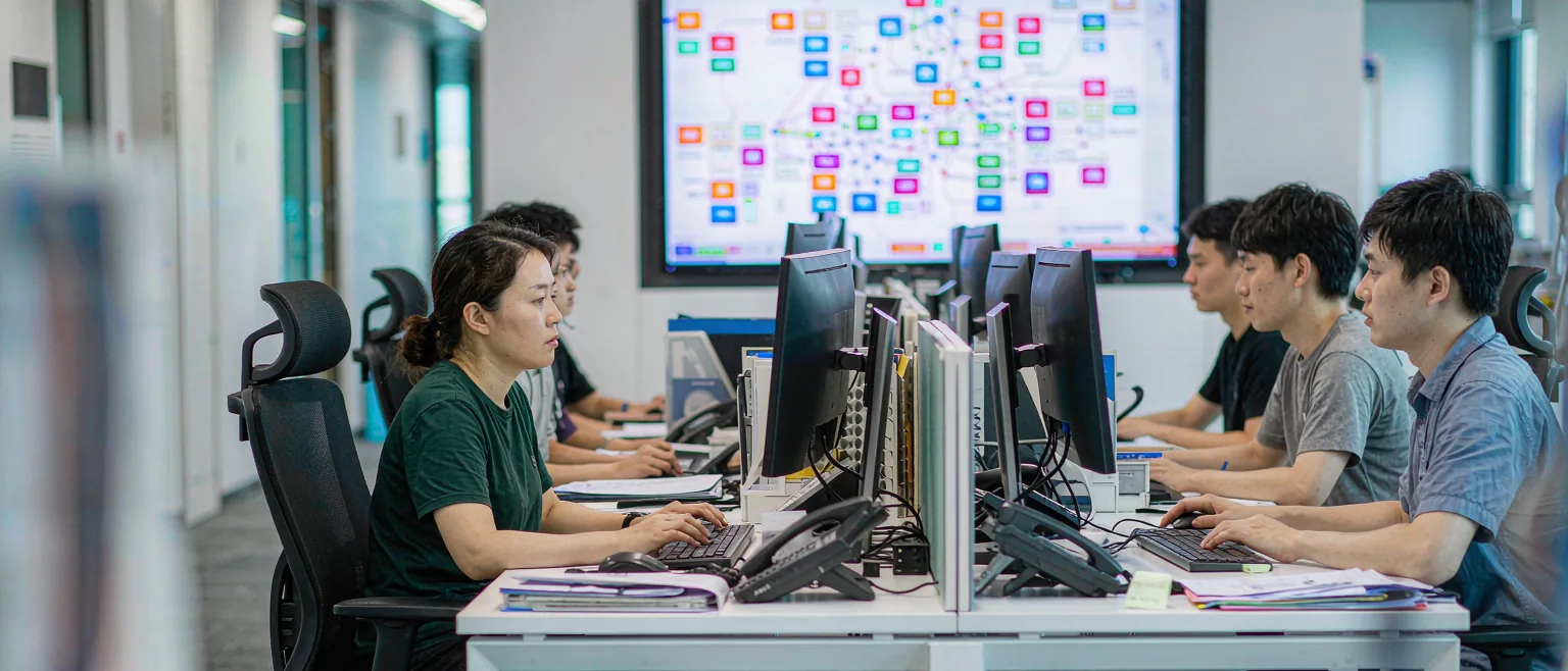 中国企业的数字化运营中心里,中国员工在工位上处理业务,墙面大屏展示业务流程拓扑图
