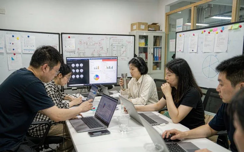 中国运营团队围坐长桌用笔记本电脑工作,大屏显示数据看板图表,身后白板画满流程图与便利贴,私域运营复盘实景,写实摄影